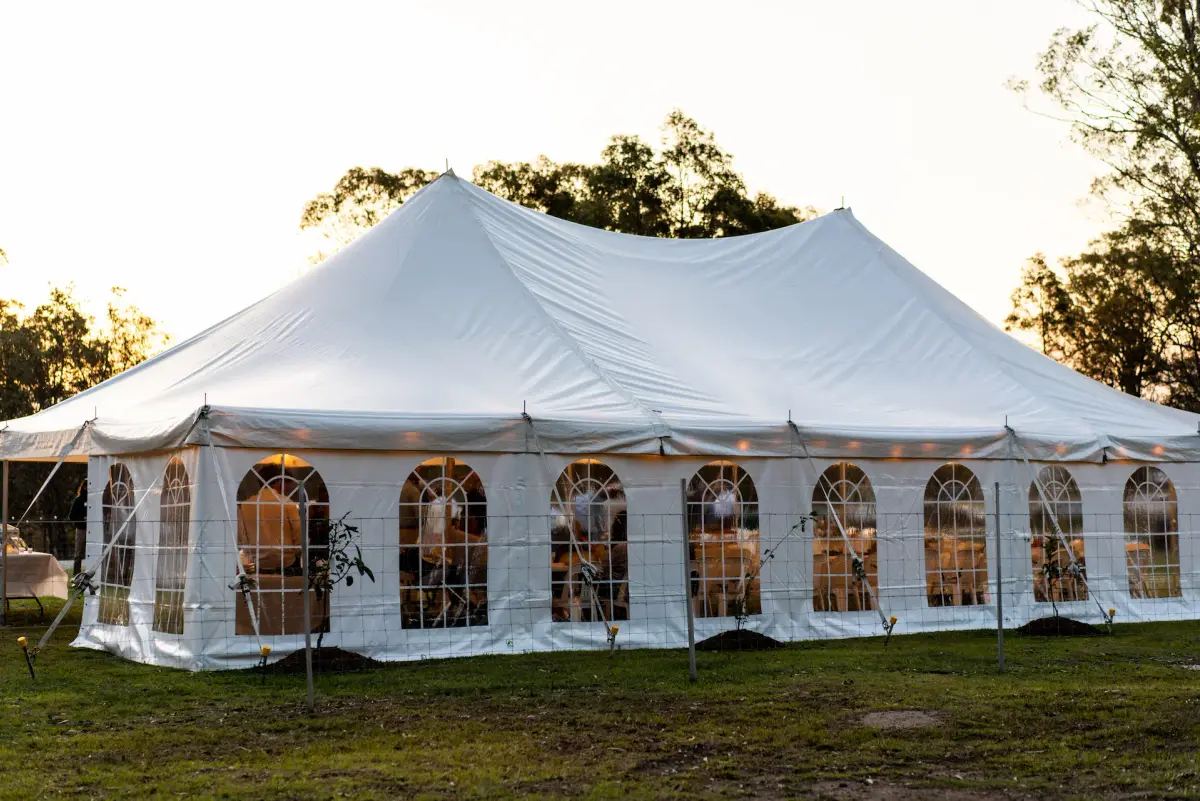 White peg-and-pole marquee with arched windows lit at sunset on a Clarence Valley paddock